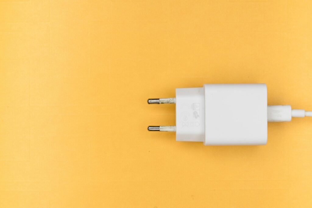 White charger plug on a clean yellow background, perfect for tech themes.