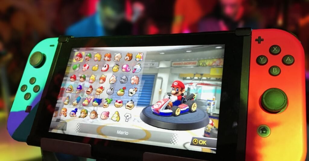Close-up of a Nintendo Switch showing Mario Kart selection screen, gaming atmosphere in the background.